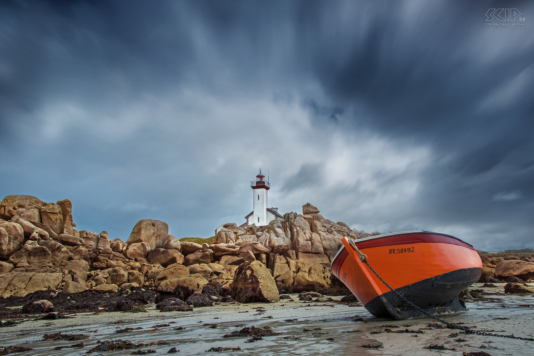 Brignogan-Plages - Phare de Pontusval Het strand met immense rotsblokken, een boot en de vuurtoren op Pointe de Beg-Pol na een hevige regenbui. De vuurtoren ('phare' in het Frans) van Pontusval werd gebouwd in 1869 en is 16m hoog. Stefan Cruysberghs